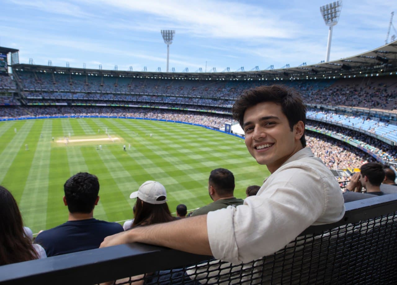 A fan turning back from the boundary rail towards the camera, the ground and a full stand behind them.